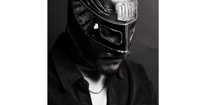 Black and white portrait of FK MENACe wearing a lucha libre mask and a corduroy jacket.